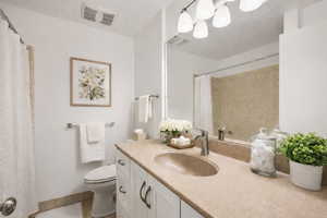 Full bath with vanity, curtained shower, light tile patterned flooring, and a textured ceiling
