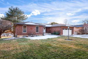 Ranch-style house featuring a front lawn, brick siding, a garage, and driveway