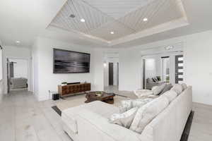 Living room featuring a tray ceiling, wood ceiling, recessed lighting, and light wood finished floors