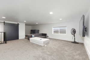 Living room with a barn door, light colored carpet, and recessed lighting