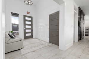 Entryway featuring a decorative wall, a wainscoted wall, crown molding, and a chandelier