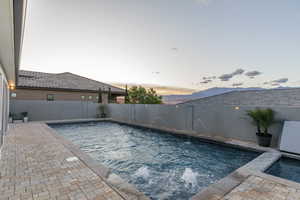 Pool at dusk with a patio and a fenced backyard