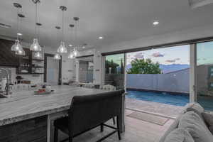 Kitchen with open floor plan, light stone countertops, decorative light fixtures, a mountain view, and wall chimney range hood