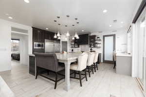 Kitchen featuring light countertops, pendant lighting, a breakfast bar, built in appliances, and open shelves
