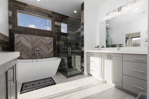 Bathroom with vanity, a freestanding tub, a shower stall, healthy amount of natural light, and recessed lighting