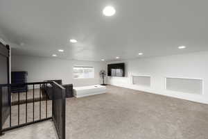 Bedroom with a barn door, light colored carpet, and recessed lighting