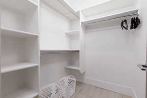 Walk in closet with light wood-type flooring