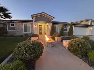 Single story home with stone siding, an outdoor fire pit, an attached garage, a front lawn, and french doors