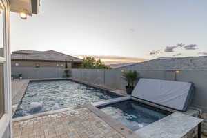 View of pool with an in-ground hot tub, a patio, and a fenced backyard