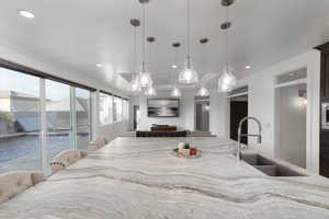 Kitchen with light stone counters, open floor plan, decorative light fixtures, recessed lighting, and a breakfast bar area