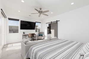 Bedroom featuring a barn door, a walk in closet, a ceiling fan, recessed lighting, and wood finished floors