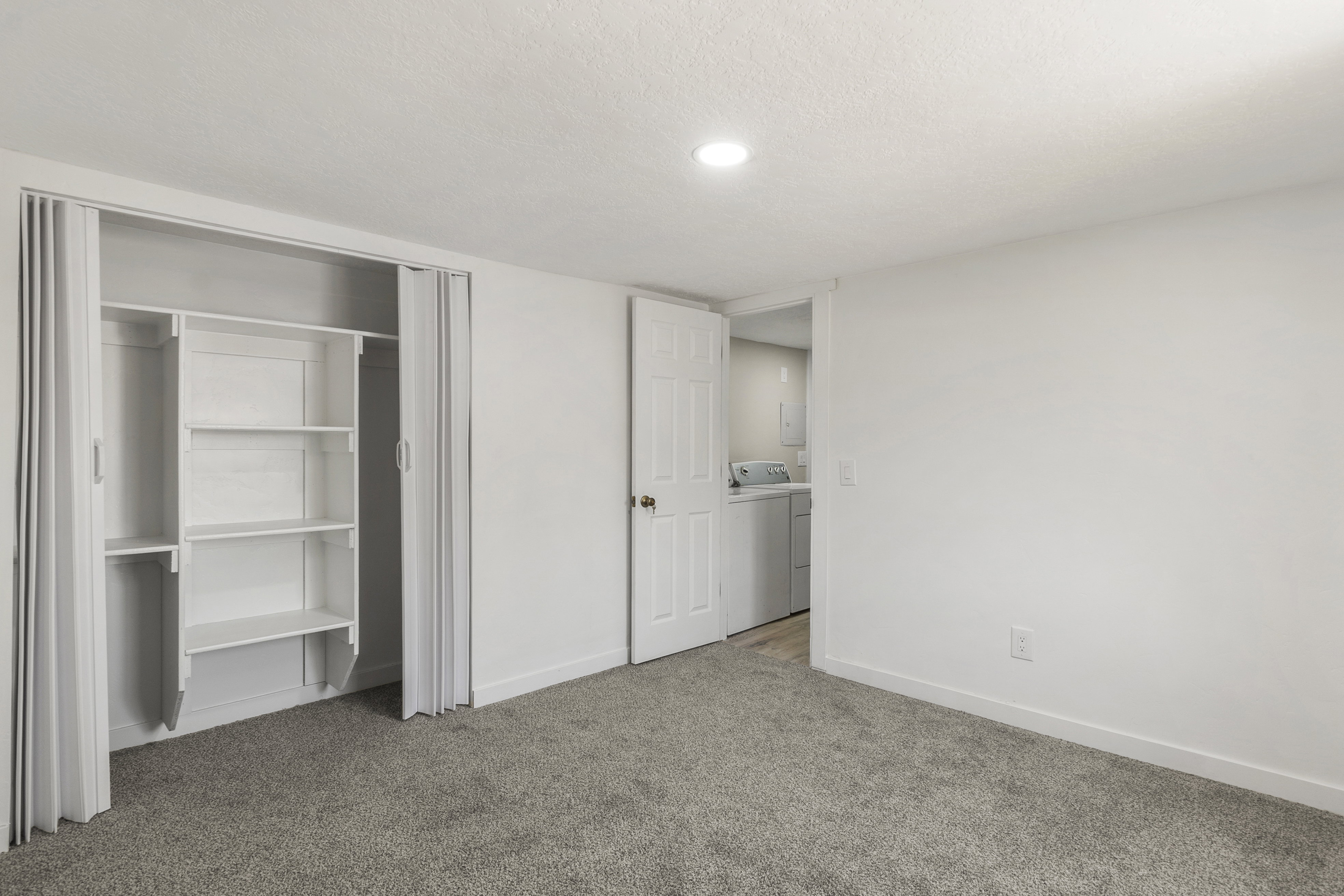 Unfurnished bedroom featuring light carpet, a textured ceiling, a closet, and washer and dryer