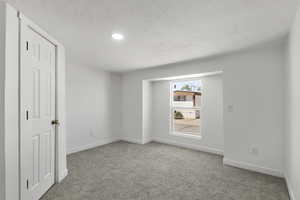 Unfurnished bedroom with light colored carpet and a textured ceiling