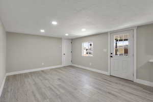 Foyer entrance featuring a textured ceiling, light wood-style floors, and recessed lighting