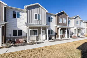 View of front of house with board and batten siding, stone siding, a porch, and a front lawn