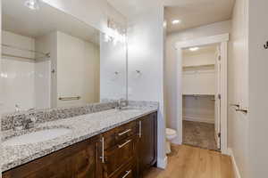 Bathroom featuring double vanity, light wood-type flooring, a spacious closet, and recessed lighting