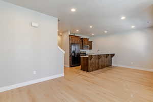 Kitchen featuring a peninsula, a kitchen bar, light wood finished floors, appliances with stainless steel finishes, and recessed lighting