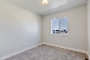 Carpeted spare room featuring baseboards