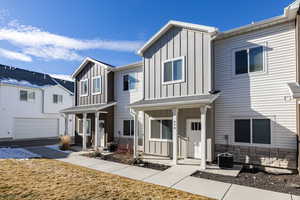 View of front of property featuring board and batten siding, stone siding, and covered porch