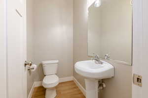 Half bath with toilet and wood finished floors