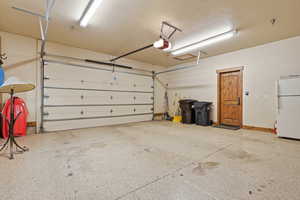 Oversized garage featuring light epoxy-coated floors and insulated door