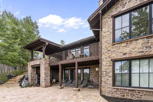 Rear view of property featuring stone siding and a patio
