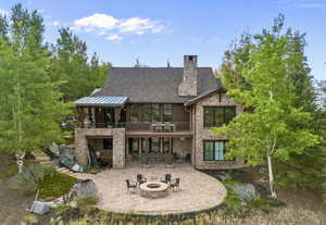 Rear view of property featuring a patio area, a balcony, stone siding, a custom stone patio with waterfall/stream & fire pit,
