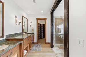 Primary bedroom suite full bath featuring a walk in closet, two vanities, a large euro-glass shower and jetted tub