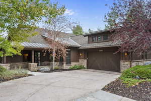 View of front of property with stone siding, driveway, and an attached garage