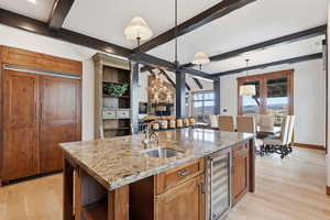 Kitchen featuring a built-in side-by-side fridge/freezer, pendant lighting, granite counters, and light oak floors