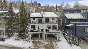 Snow covered rear of property with a chimney, a patio area, and an attached garage