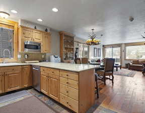 Kitchen featuring light stone countertops, backsplash, a chandelier, open floor plan, and appliances with stainless steel finishes