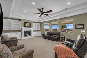 Living room with recessed lighting, light carpet, a glass covered fireplace, and ceiling fan