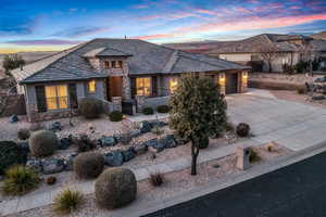 View of front of property featuring stone siding, concrete driveway, a garage, and stucco siding