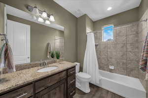 Full bath featuring vanity, shower / tub combo with curtain, and dark wood-style floors