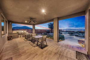 Fenced backyard with a ceiling fan and an outdoor kitchen / dining area