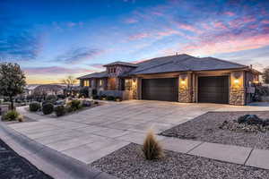 Prairie-style home featuring stone siding, an attached garage, concrete driveway, stucco siding, and a tile roof