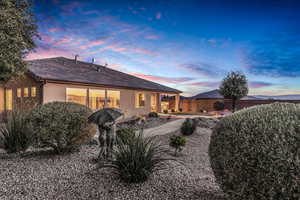 Back of house at dusk featuring stucco siding, a fenced backyard, and a patio area
