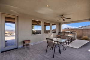 Wooden terrace featuring outdoor dining area, a patio, exterior kitchen, and ceiling fan