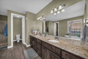 Bathroom with double vanity, dark wood-style floors, and a garden tub