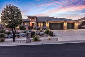 Prairie-style house featuring stone siding, stucco siding, driveway, an attached garage, and a tiled roof