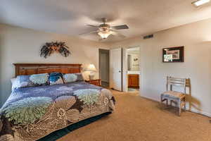 Bedroom featuring ensuite bath, light colored carpet, a textured ceiling, and ceiling fan