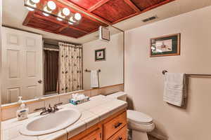 Bathroom with curtained shower, vanity, and a textured wall