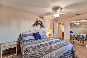 Bedroom with carpet flooring, a closet, ceiling fan, and a textured ceiling