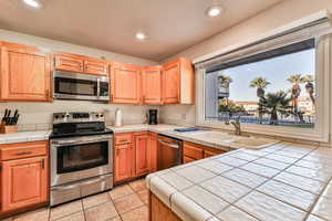 Kitchen featuring stainless steel appliances, recessed lighting, tile counters, and light tile patterned flooring