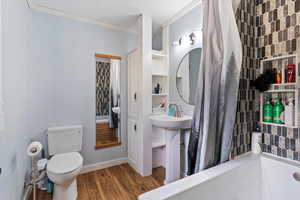 Full bathroom featuring crown molding, dark wood finished floors, and shower / bath combo