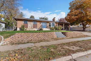 Single story home featuring roof mounted solar panels, a chimney, a trampoline, and brick siding