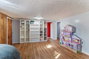 Bedroom featuring light wood-style floors, a textured ceiling, and a closet