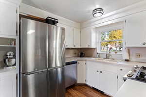 Kitchen with appliances with stainless steel finishes, light countertops, white cabinetry, and dark wood-type flooring