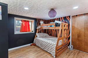 Bedroom with wood finished floors, recessed lighting, and a textured ceiling